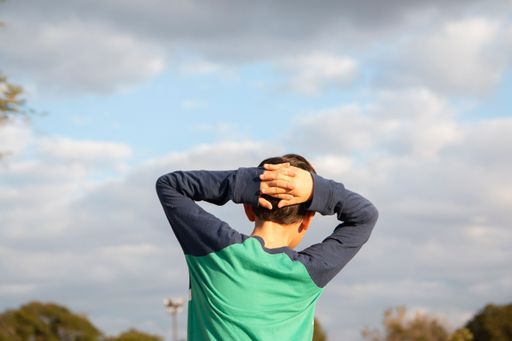 A back view of boy with hands on head looking towards