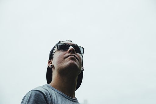 A low angle shot of a cool young man wearing sunglasses and a hat