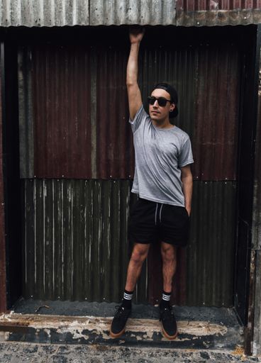A vertical shot of a stylish young man posing in front of a garage wall