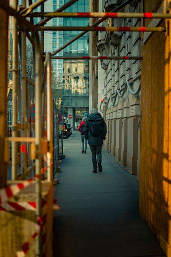 A vertical view of people walking on a pavement shot from behind