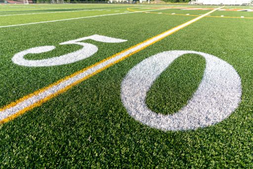 Example of a new synthetic turf football field at the fifty, 50, yard line in white.