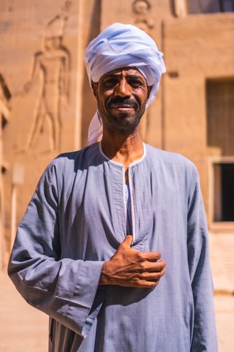 Aswan, Egypt '; October 14, 2020: Two Nubian workers in turbans guarding the beautiful Temple of Philae and accompanying a young tourist, a Greco-Roma