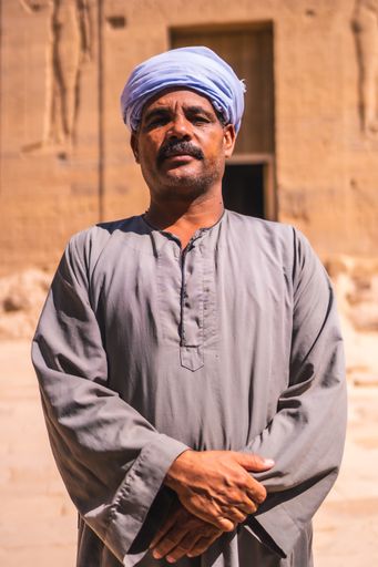 Aswan, Egypt '; October 14, 2020: Two Nubian workers in turbans guarding the beautiful Temple of Philae and accompanying a young tourist, a Greco-Roma