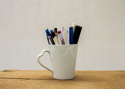 A group of pens in a white cup on white background