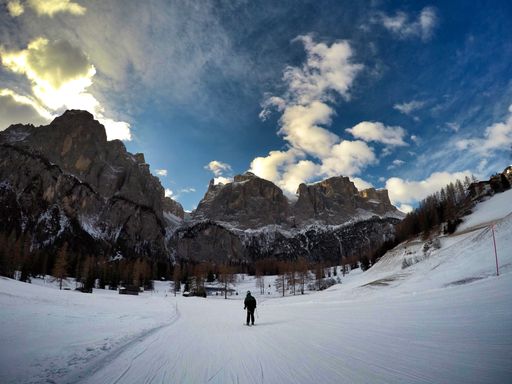 A back view of a skier skiing on a snow-covered landscape with immense rock formations in front