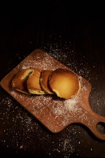 A vertical high angle shot of freshly baked pancakes on a chopping board covered with baking powder on a wooden surface