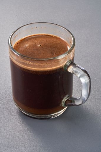 a glass of brewed coffee in a transparent cup with crema on top
