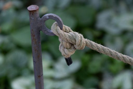 A closeup of a thick rope knot tied to a piece of metal