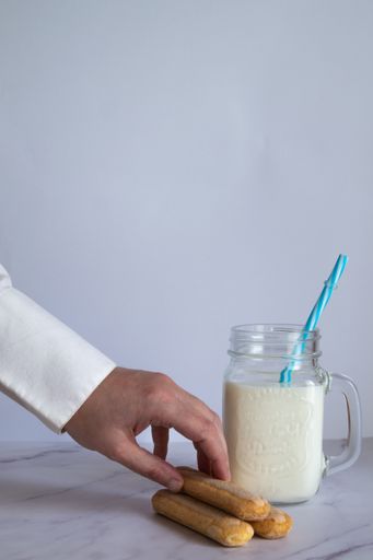 A vertical shot of a male wants to dip cookie on a milkshake