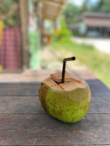 A vertical shot of a fresh coconut with a straw on a wooden table