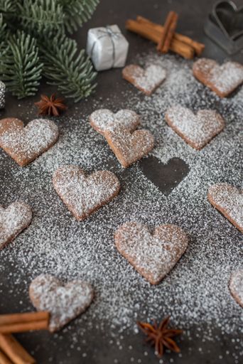 A high-angle view of gingerbread heart cookies with white powder on them put on the gray surface