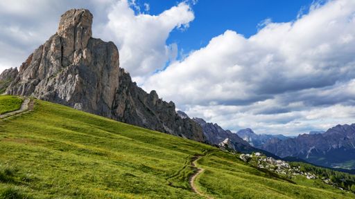 A mesmerizing landscape of a green valley and rocky mountains on a cloudy day