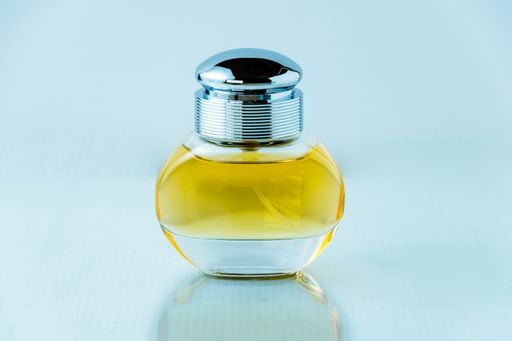 A closeup of a bottle of perfume on the table under the lights against a blurry background