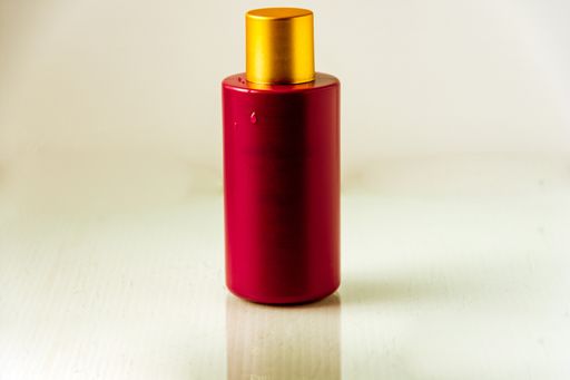 A closeup of a bottle of perfume on the table under the lights against a blurry background