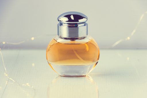 A closeup of a bottle of perfume with lights on it on the table