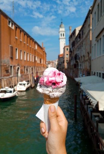 A vertical shot of a person holding a delicious ice cream in front of a city view
