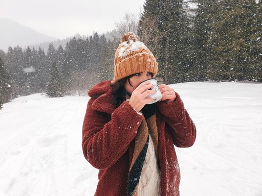 A beautiful shot of female drinking from her mug outdoors on a snowy day