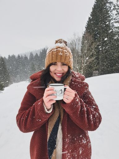 A vertical shot of a caucasian female with a cup of hot drink outdoors in winter