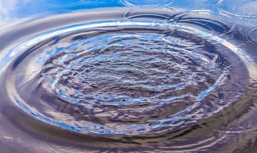 Beautiful water at a lake with splashing water and ripples on the surface with clouds and sky reflections