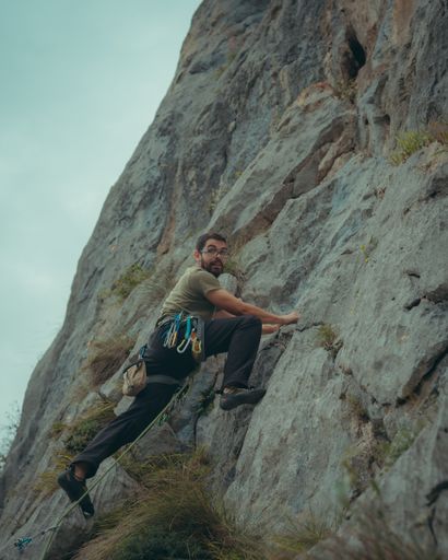 A vertical shot of a young male climbing a mountain