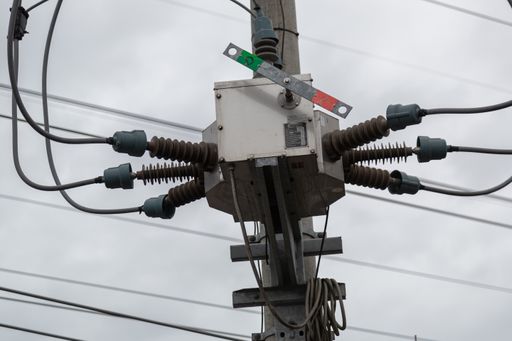 A low angle shot of an electrical power post under a cloudy sky