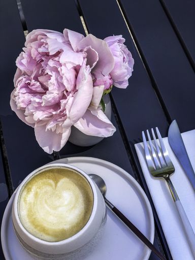A vertical top view of cappuccino served with a rose on table