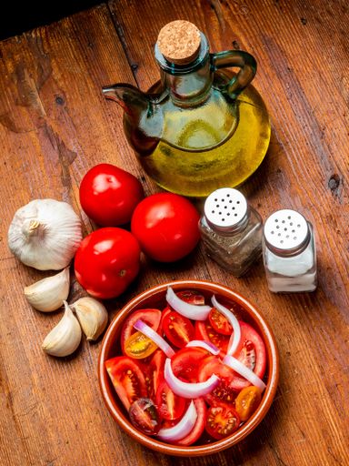 A high angle shot of a salad with tomatoes, onion and olive oil