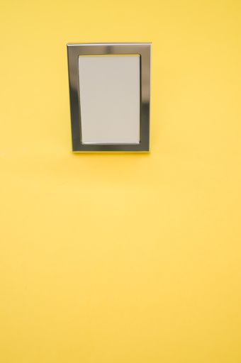 A vertical shot of a picture frame on yellow background