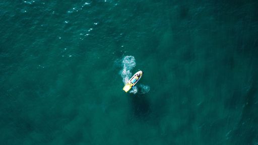 An aerial shot of a small boat alone in the turquoise water