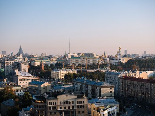 A high angle shot of city buildings with cars driving on the street under a blue sky at Russia