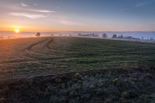 The view of a landscape before the steam-covered lake under the blue morning sky
