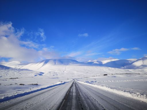A scenic view of a path passing through a landscape covered entirely by snow