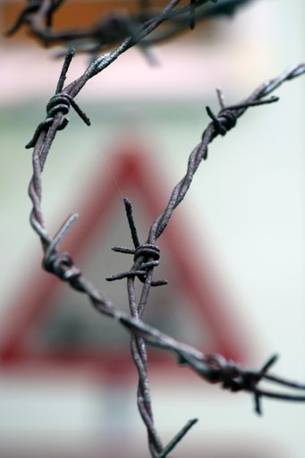A vertical selective focus shot of barbed wires `forming ties