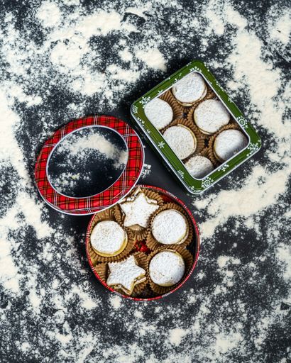 A vertical top view of Christmas metal boxes with cookies inside them