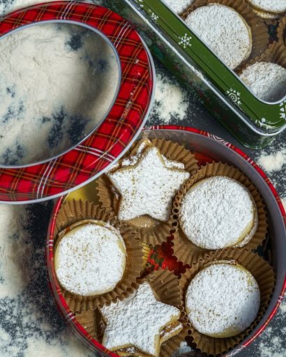 A vertical top view of Christmas metal boxes with cookies inside them