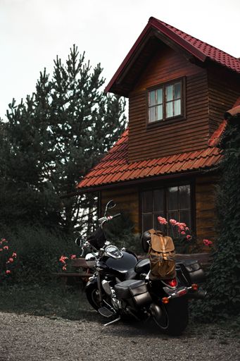 A vertical shot of a vintage big bike parked outside a two-story house