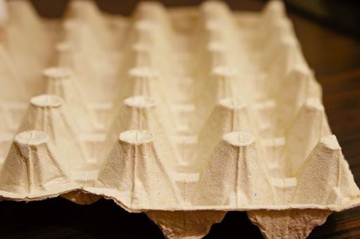 A closeup of a paper box for eggs on a wooden table on a blurry background