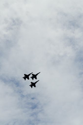 A low angle shot of three fighter jets flying on a gloomy day background