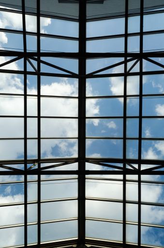 A low angle shot of a modern glass roof with a cloudy sky background