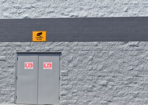 A closeup shot of a modern industrial building exterior wall sign with an inscription ''Cameras In Use''