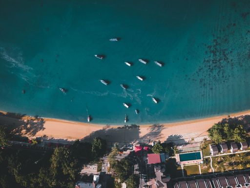 A high-angle shot of a tropical coast with boats on the water.