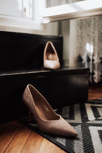 A vertical shot of a pair of beige shiny high-heels for the bride on her wedding day, on a  floor