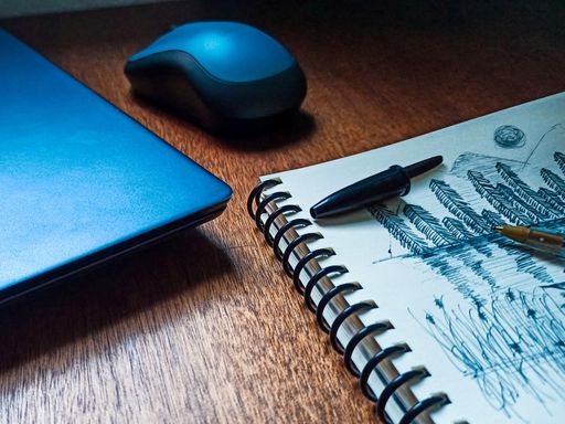 A closeup of a simple nature sketch on a sketchbook near a laptop on the table