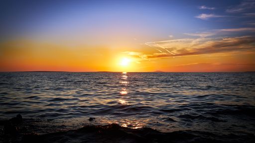A beautiful view of a blue sea under the clear sky during sunset