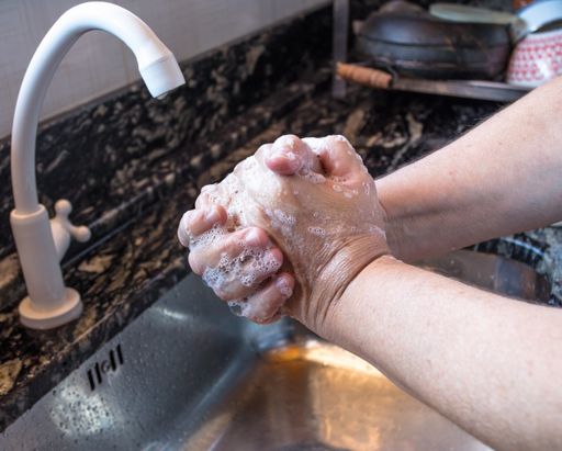 A female washing her hands with soap in the kitchen during lockdown caused by the covid-19 pandemic