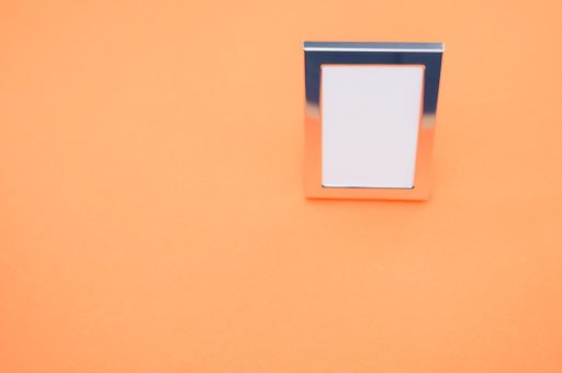 A high angle shot of a small simple photo frame isolated on a light orange background