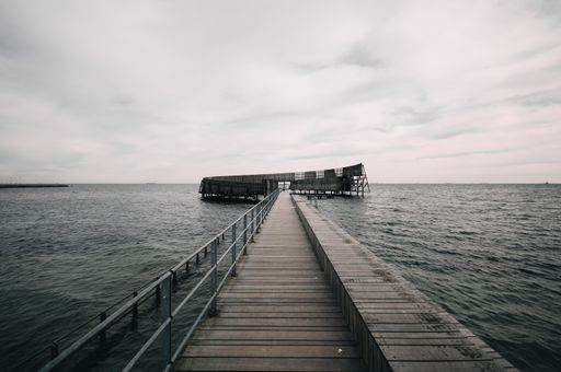 A pier leading to the calm ocean under the gloomy sky