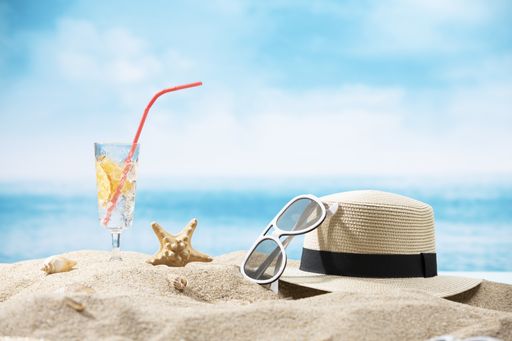 A hat, sunglasses, starfish and a glass of lemon water on an ocean background