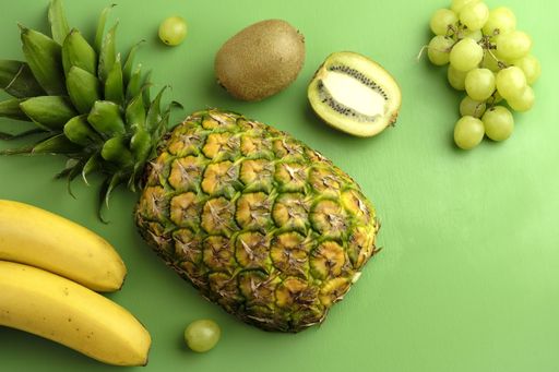 A high angle closeup shot of assorted mixed fruits on a green background