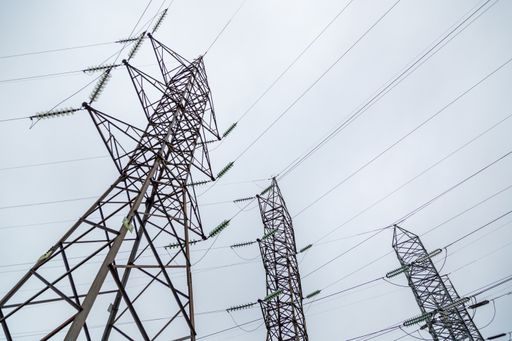 A low angle shot of high voltage powerlines on a gloomy day background